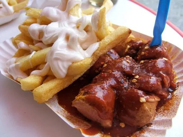 Alt: Hình ảnh món Currywurst, một loại xúc xích Đức nổi tiếng được phủ sốt cà ri và cà chua, thường được ăn kèm khoai tây chiên.